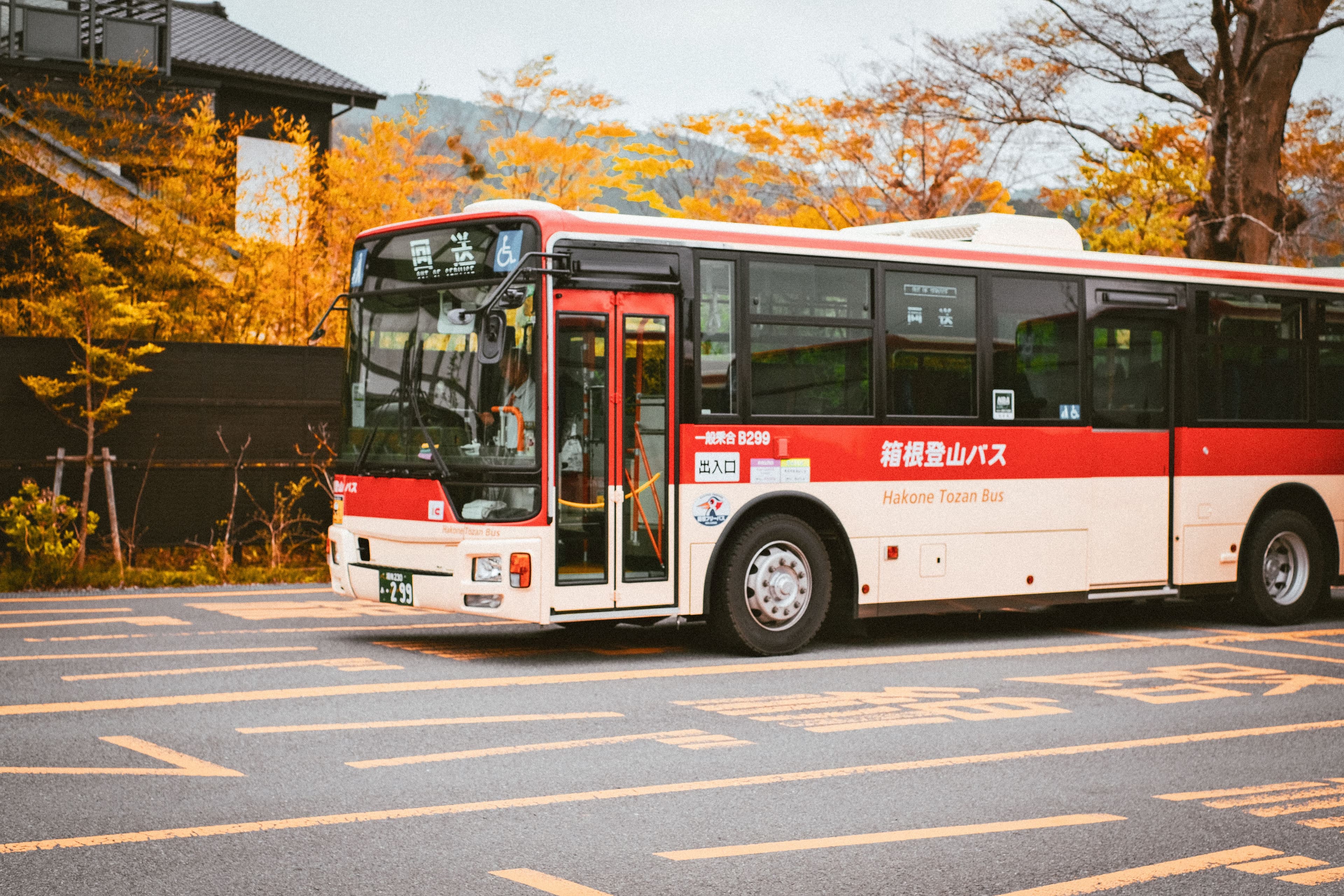 A Hakone Tozan Bus on a Japanese road with autumn colors behind it