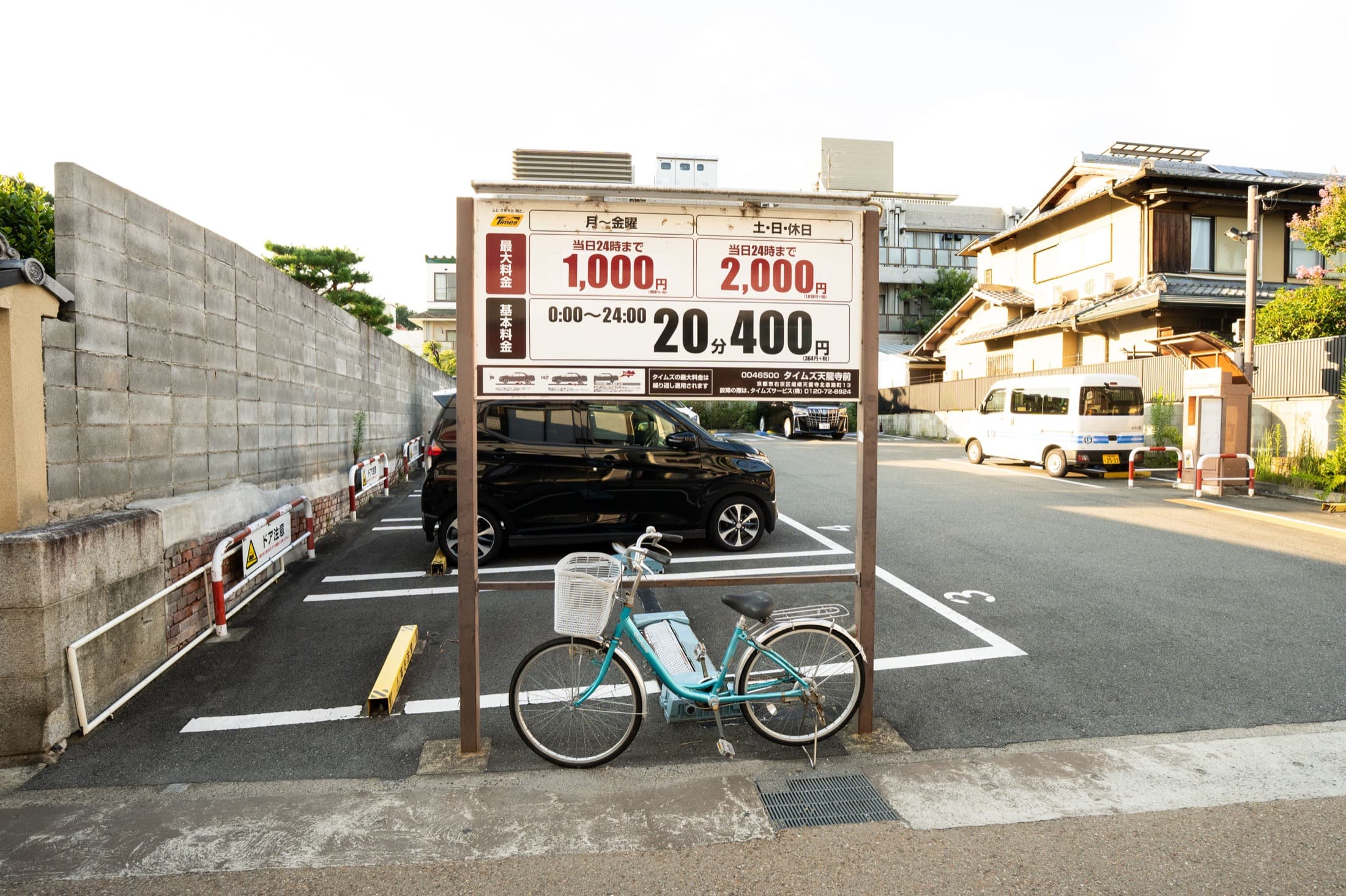 A Japanese coin parking lot with a posted price board and numbered parking spaces