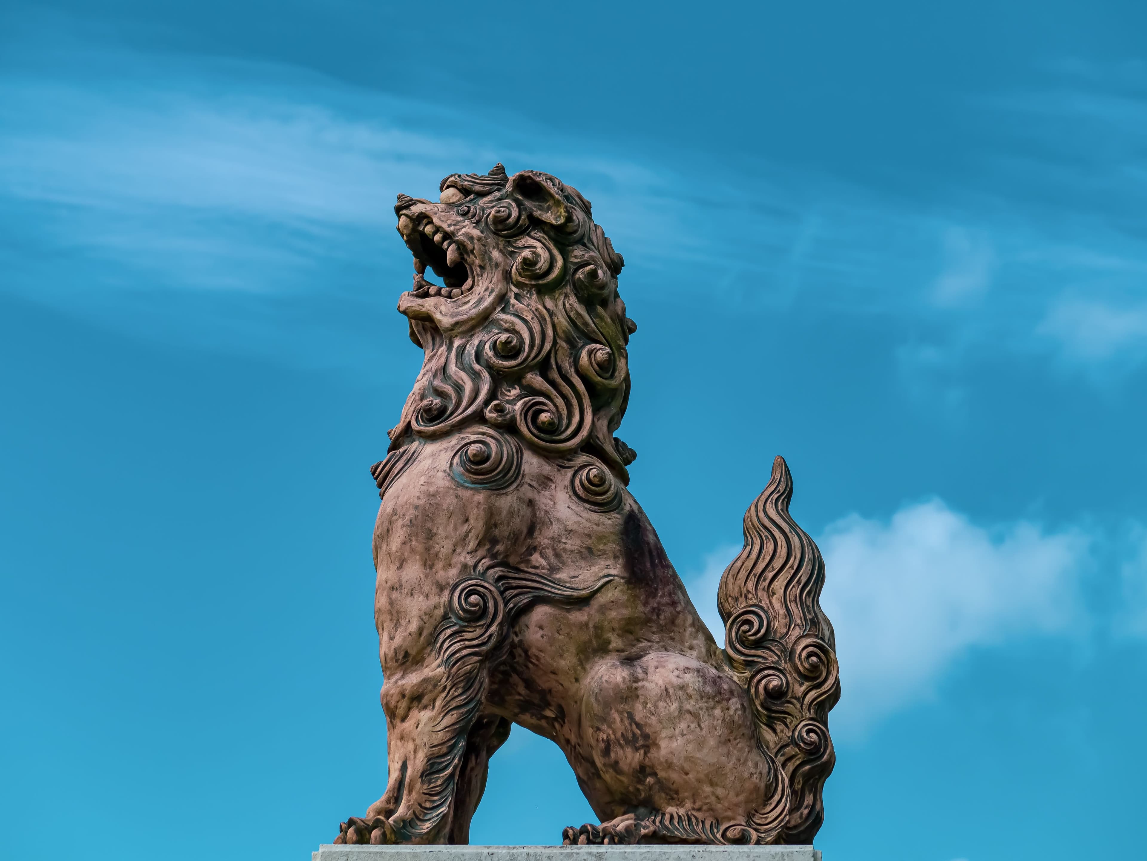 An Okinawan shisa guardian lion statue standing beneath a bright blue sky