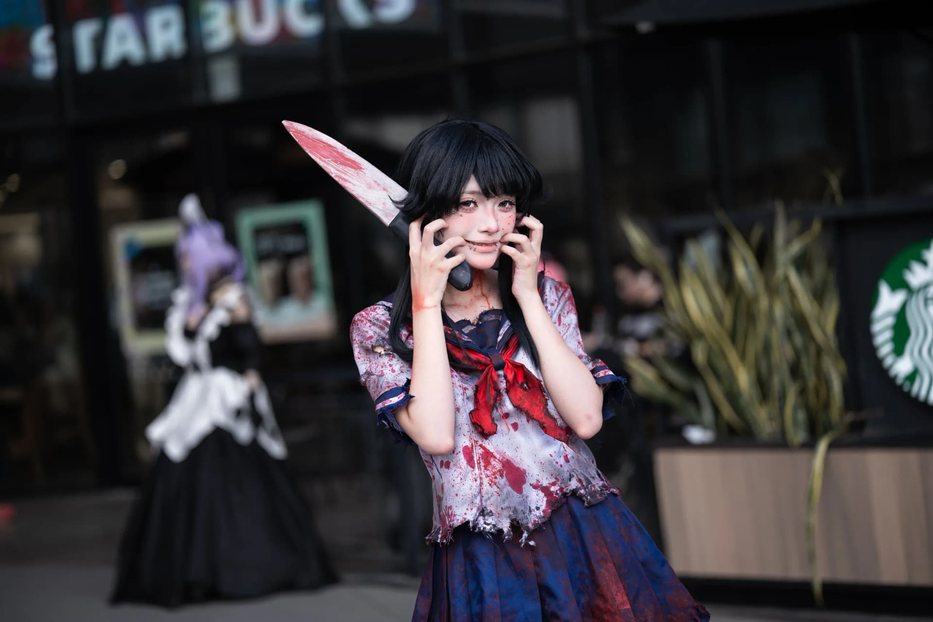A Halloween cosplayer in a blood-stained costume poses on a city street in Japan