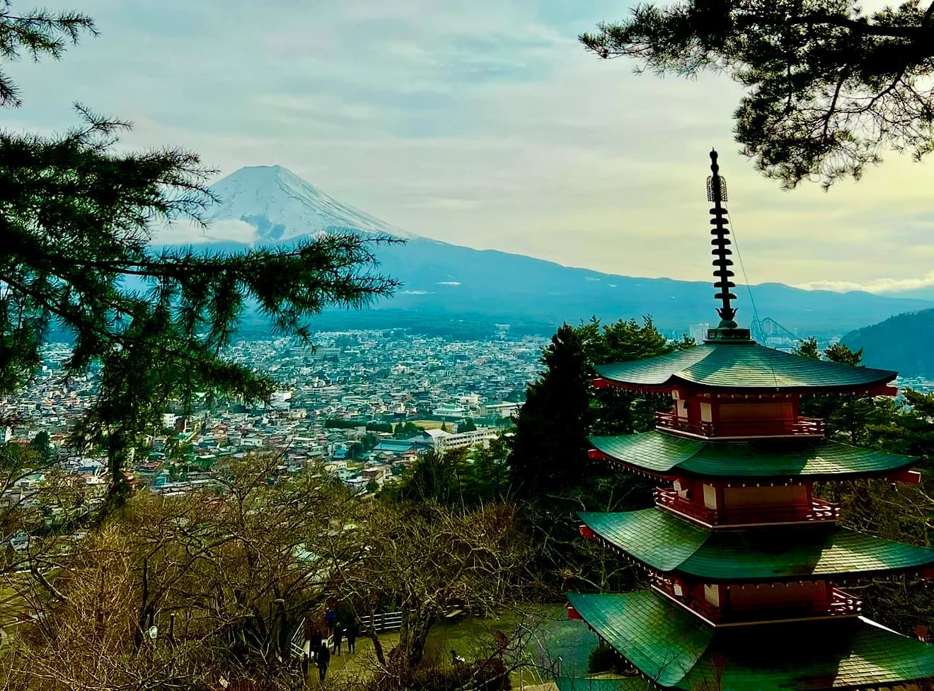 Mount Fuji beyond Fujiyoshida, with Chureito Pagoda and pine branches in the foreground