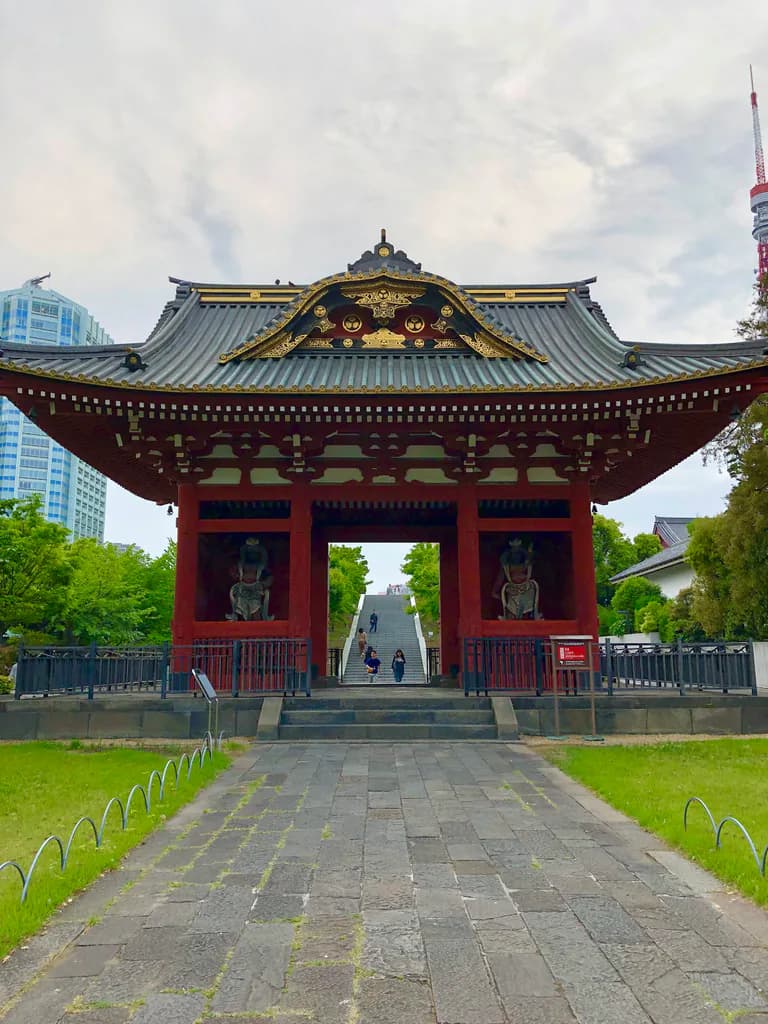 Zojoji's red temple gate beneath an overcast sky, with part of Tokyo Tower visible on the right